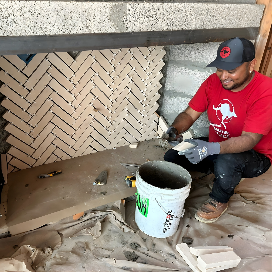Mason laying herringbone tile on fireplace surround
